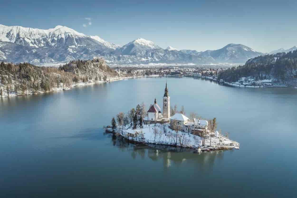 Bled Lake island church in winter with snow-covered mountains in Slovenia