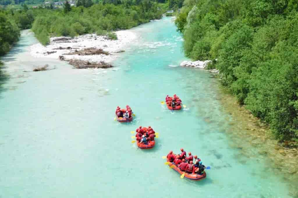 White water rafting in Slovenia on a turquoise river surrounded by lush green forest.