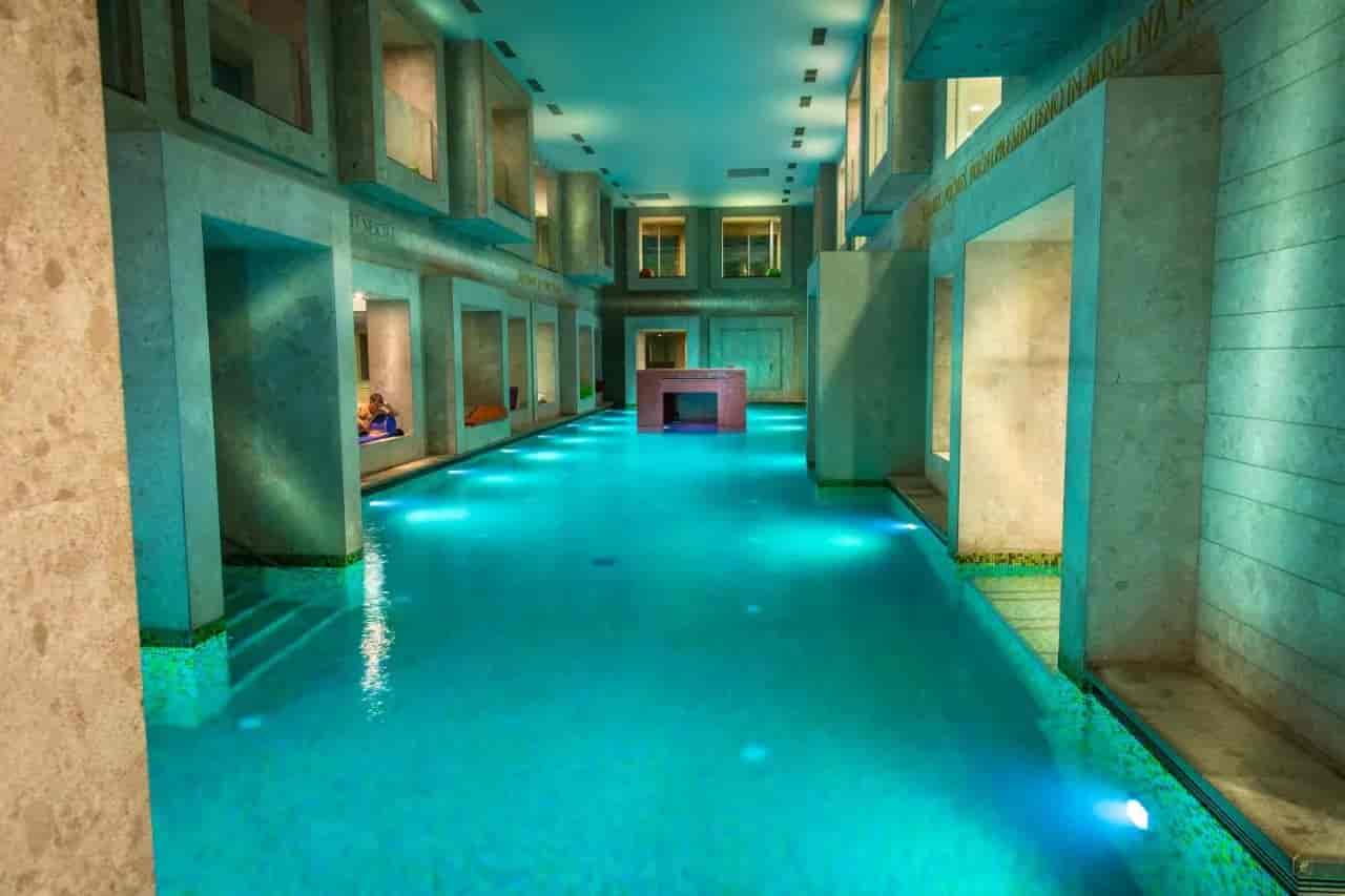 Indoor thermal pool with turquoise lighting and stone architecture, Rimske Terme.
