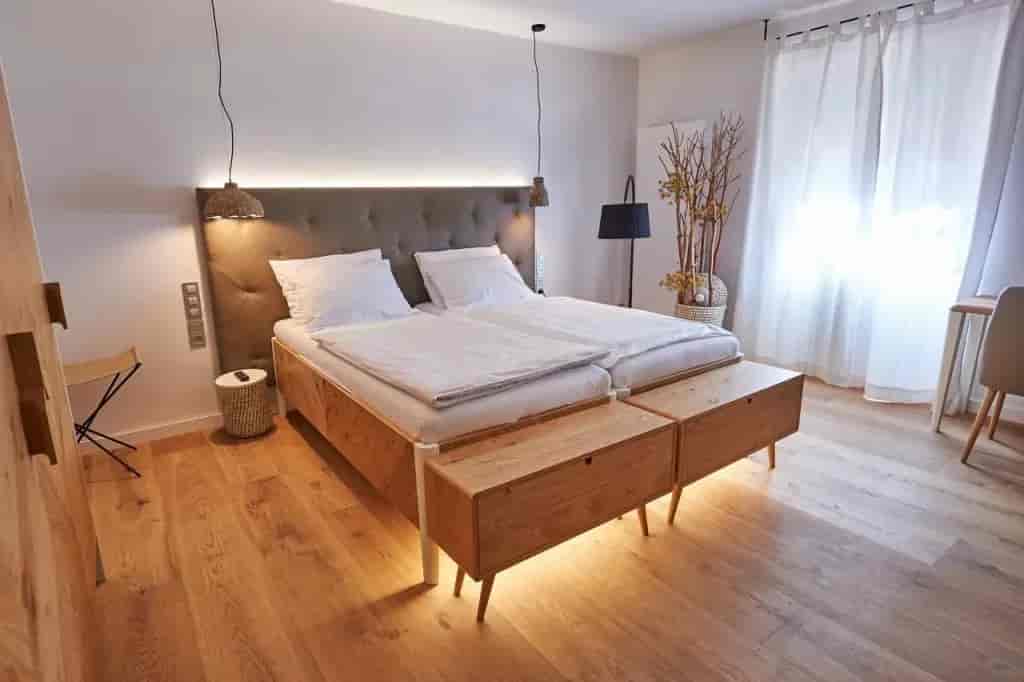 Hotel room with twin beds, light wood floors, and bright sheer curtains at Hotel Plesnik.