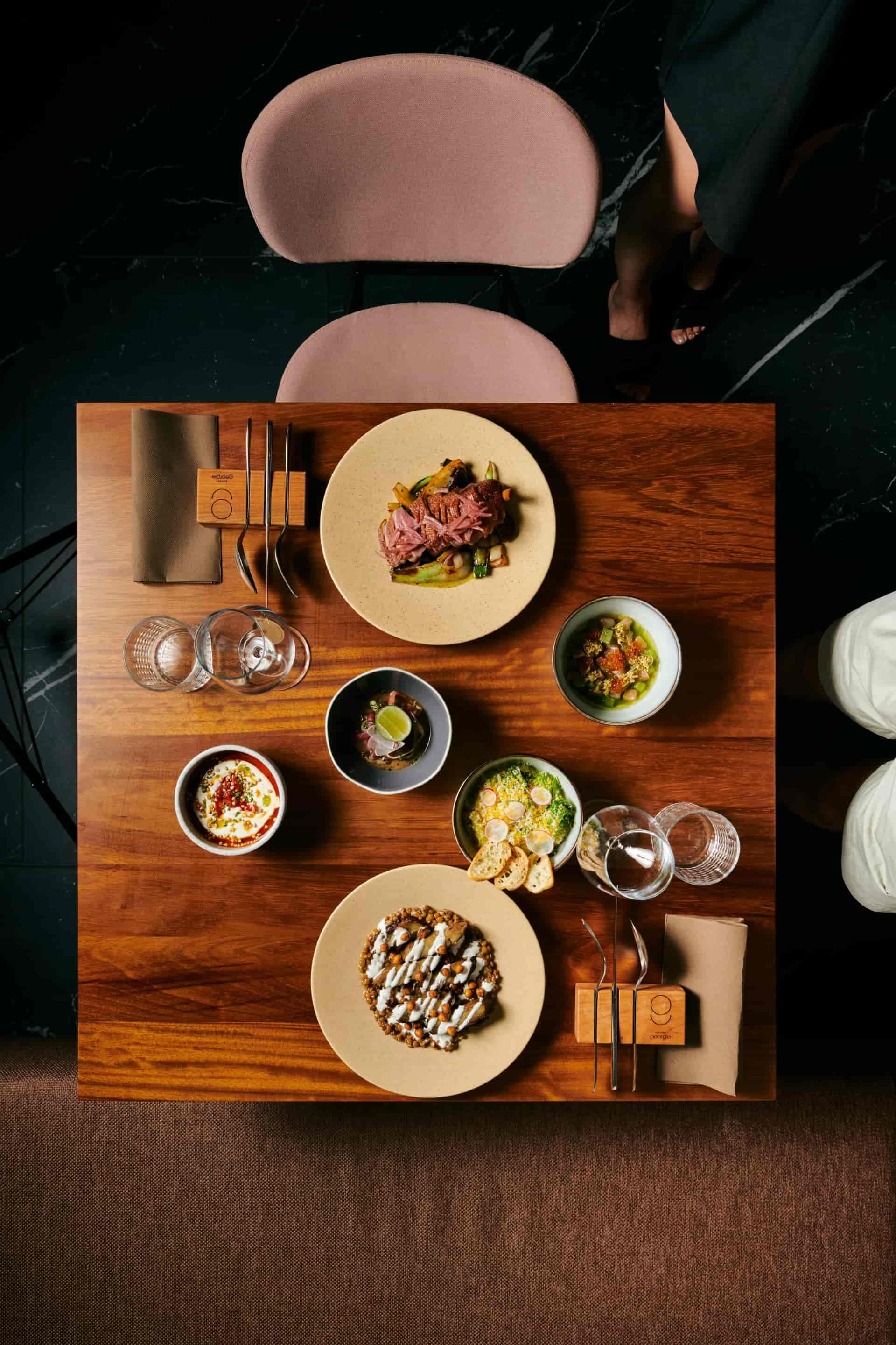 Overhead view of multiple gourmet dishes served on a wooden table at Georgie Bistro.