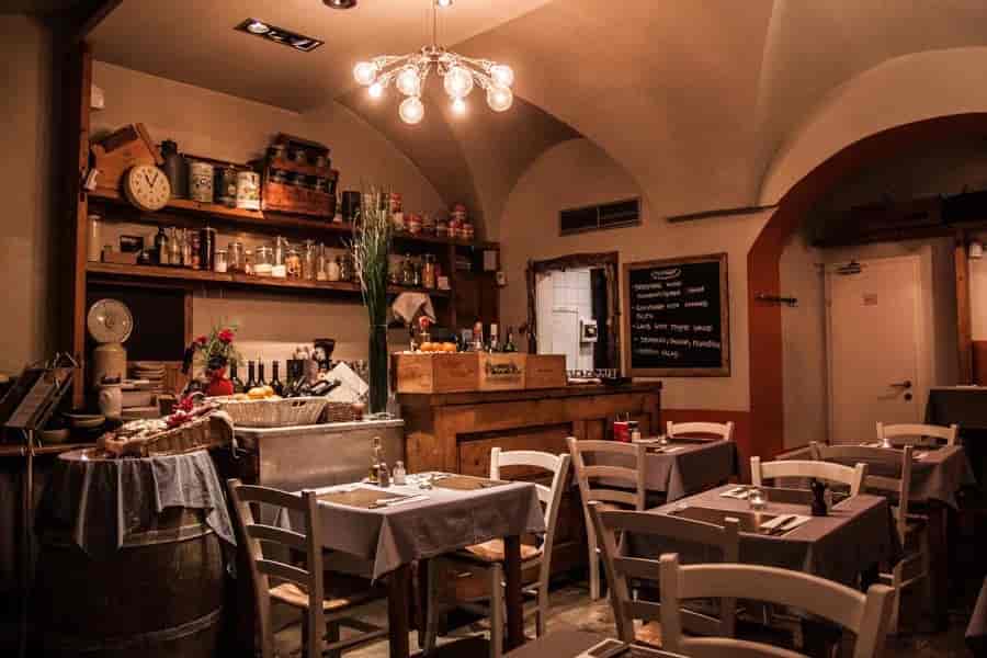 Cozy restaurant interior with vaulted ceiling, wooden counter, and set dining tables.
