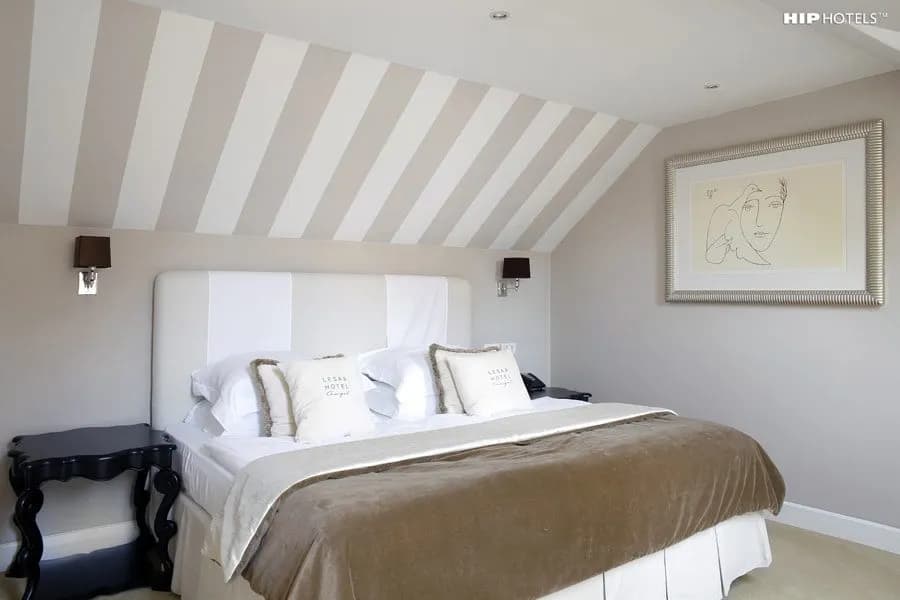 Bedroom in Lesar Hotel with striped vaulted ceiling and framed modern art.