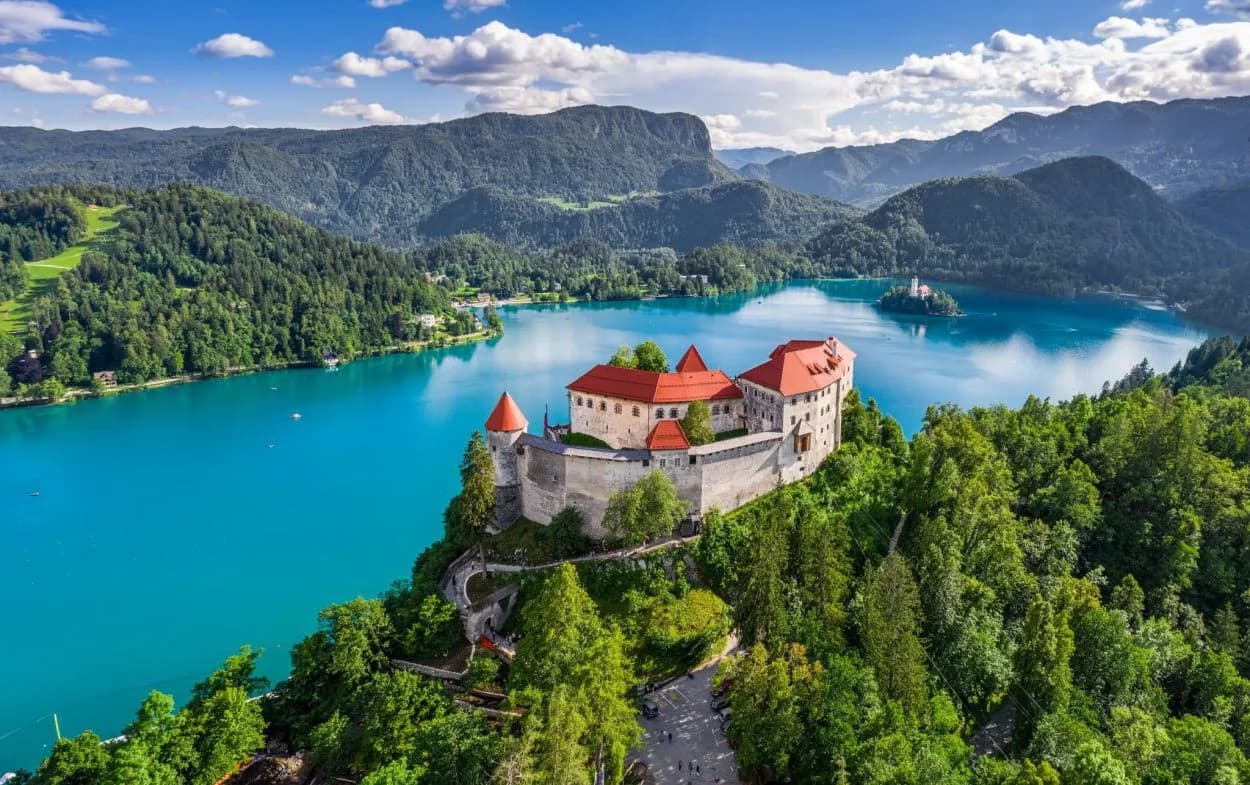 Lake Bled Castle overlooking bright blue water with island church and forested mountains.