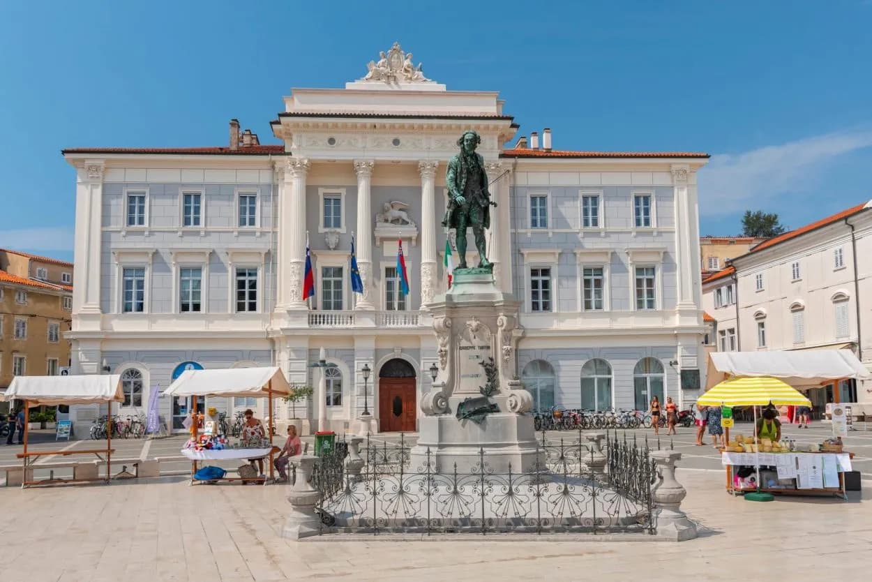Statue in front of Tartini House in Piran Old Town square with market stalls
