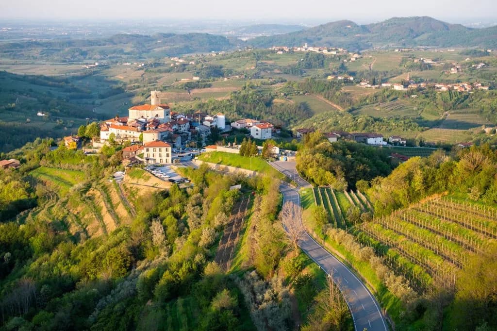 Hilltop village of Goriška Brda surrounded by lush green vineyards and rolling hills.