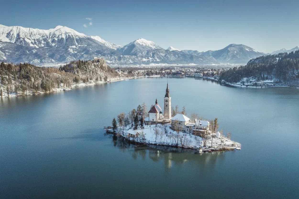 Bled Lake island church in winter with snow-covered mountains in Slovenia