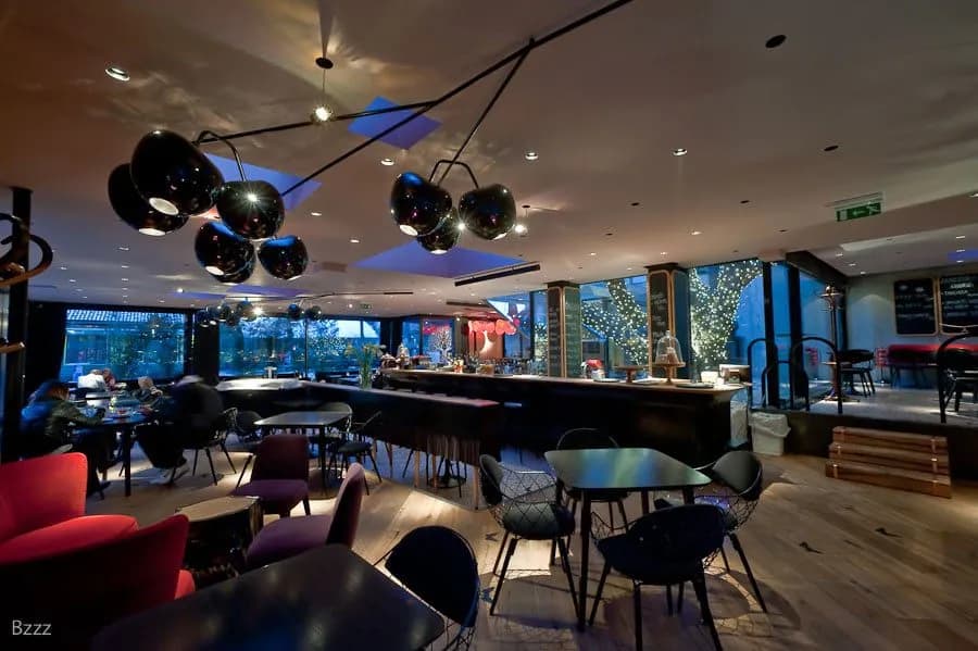 Modern aperitivo restaurant interior with unique cherry-shaped pendant lights and dark furnishings.