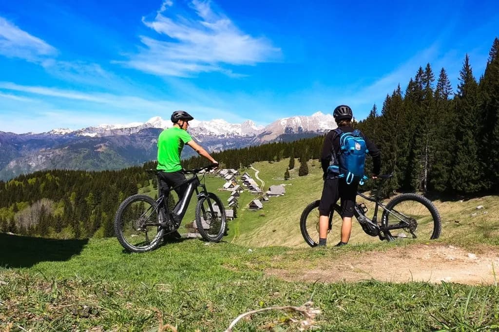 Mountain biking with views of snow-capped mountains and the Zajamniki Pokljuka settlement.