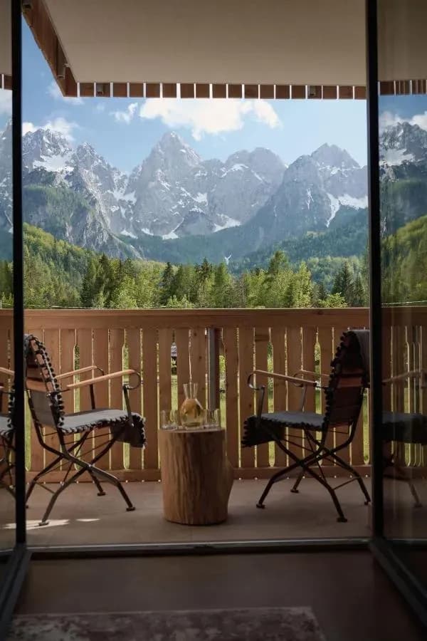Balcony with chairs overlooking snow-capped mountains and green forest, Triangel Hotel Sobe.