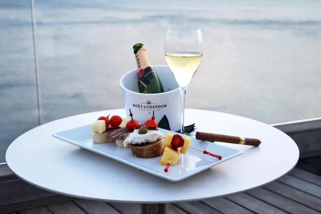 Snacks, champagne in ice bucket, and cigar on white table overlooking the sea at Hotel Piran.