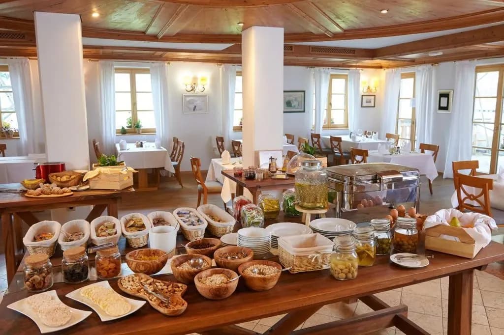 Hotel breakfast buffet with cereals, fruit, and hot food in a room with wood ceilings.