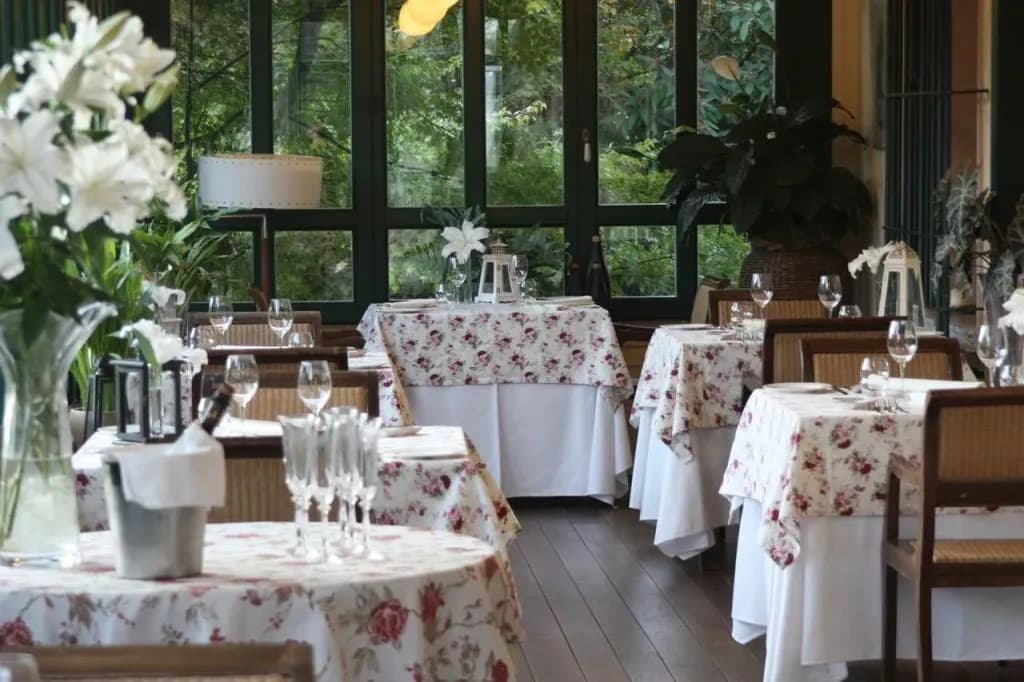 Dining area in Dobra Vila boutique hotel with floral tablecloths and view of greenery.
