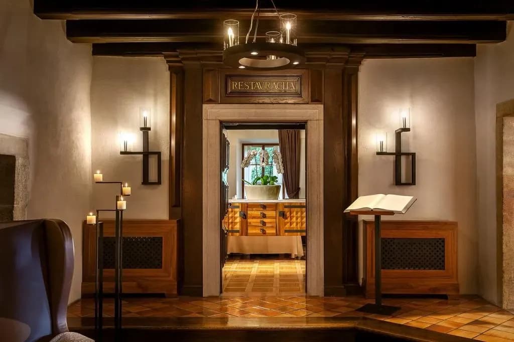 Restaurant entrance with dark wood trim, ambient lighting, candles, and an open book on a stand.