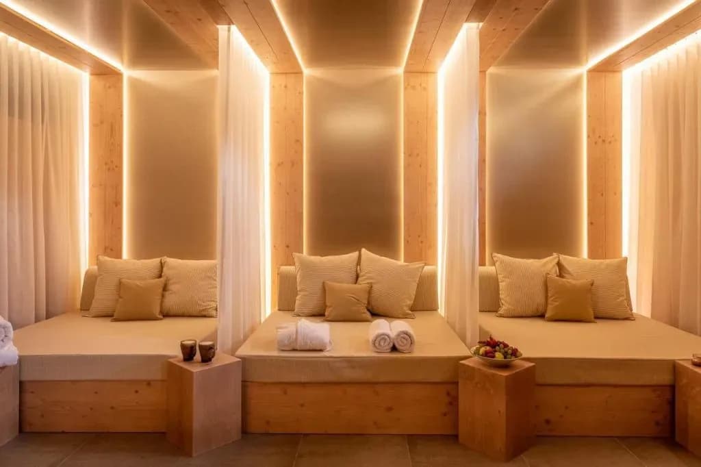 Three wooden relaxation beds with soft pillows and ambient lighting in a spa area.