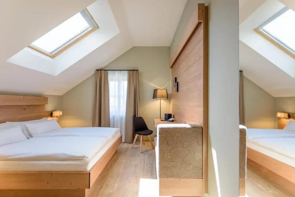 Attic hotel room with wooden bed, skylight, and light wood flooring