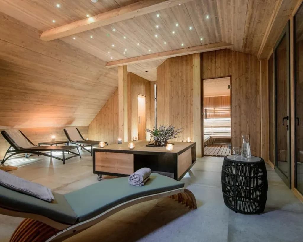 Relaxation area with wood paneling, lounge chairs, and view into a sauna at Vila Planinka.