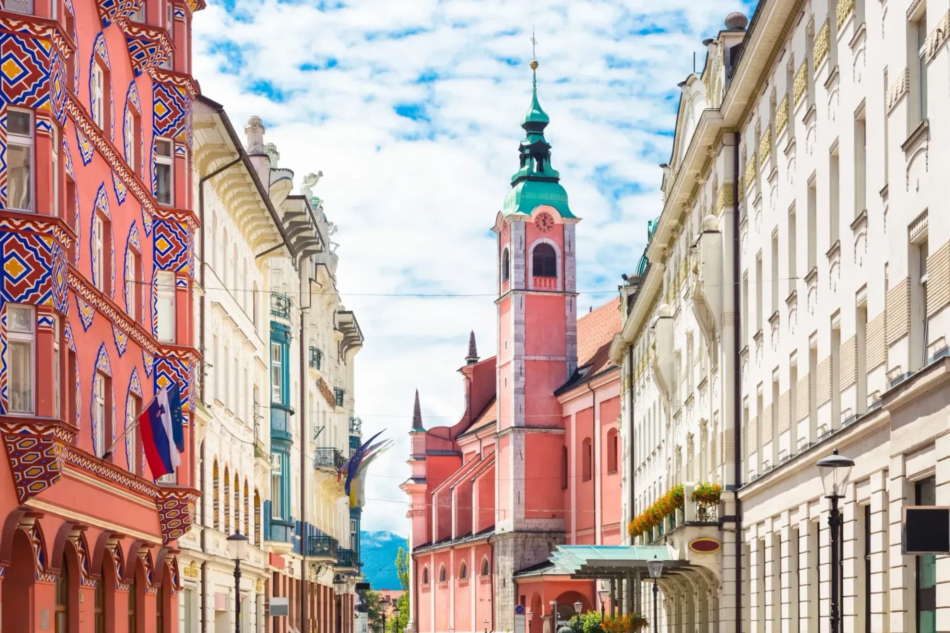 Pink church tower and colorful historic buildings on a street in Ljubljana, Slovenia.