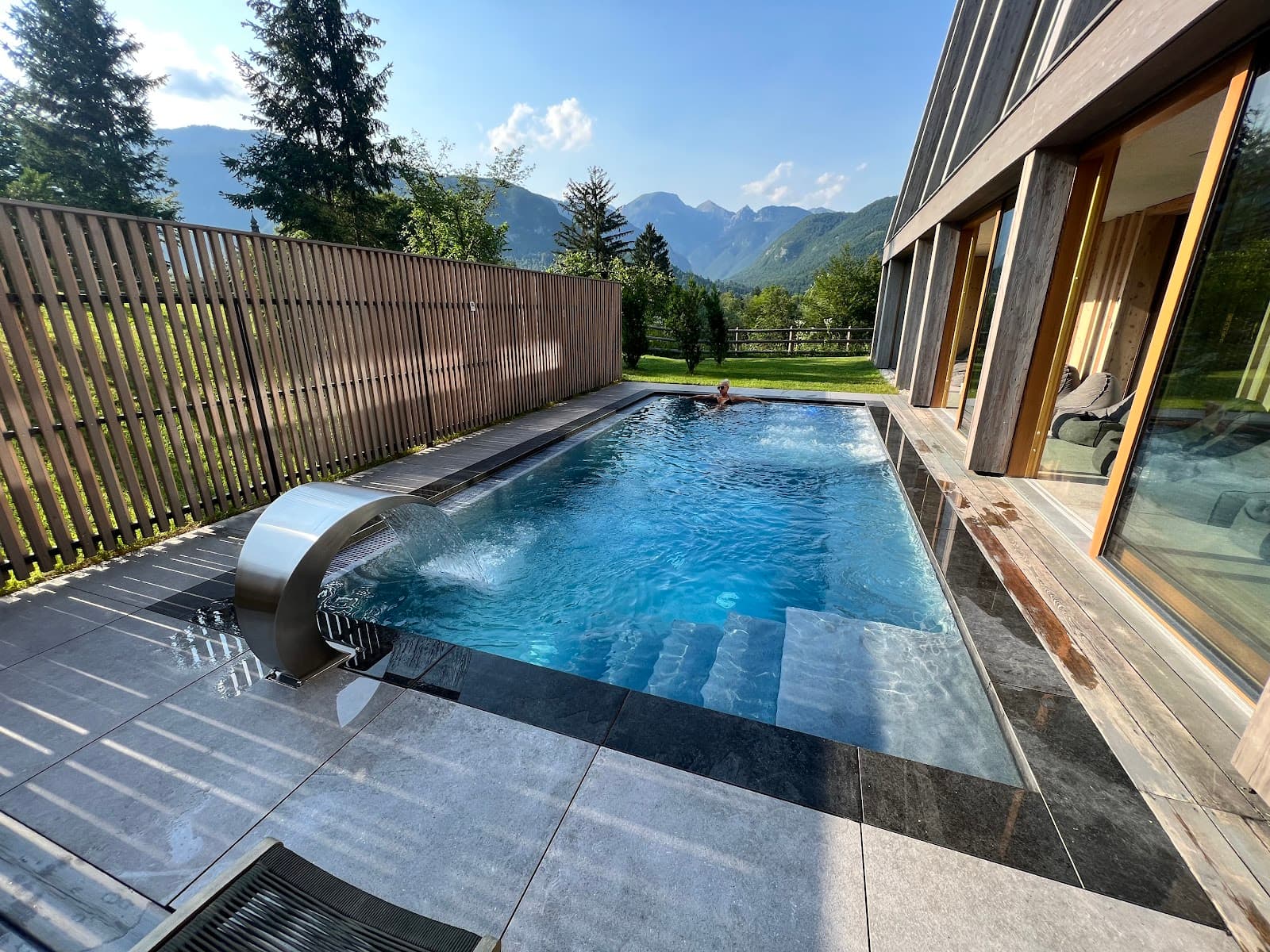 Outdoor swimming pool with waterfall feature overlooking mountains near Bohinj.
