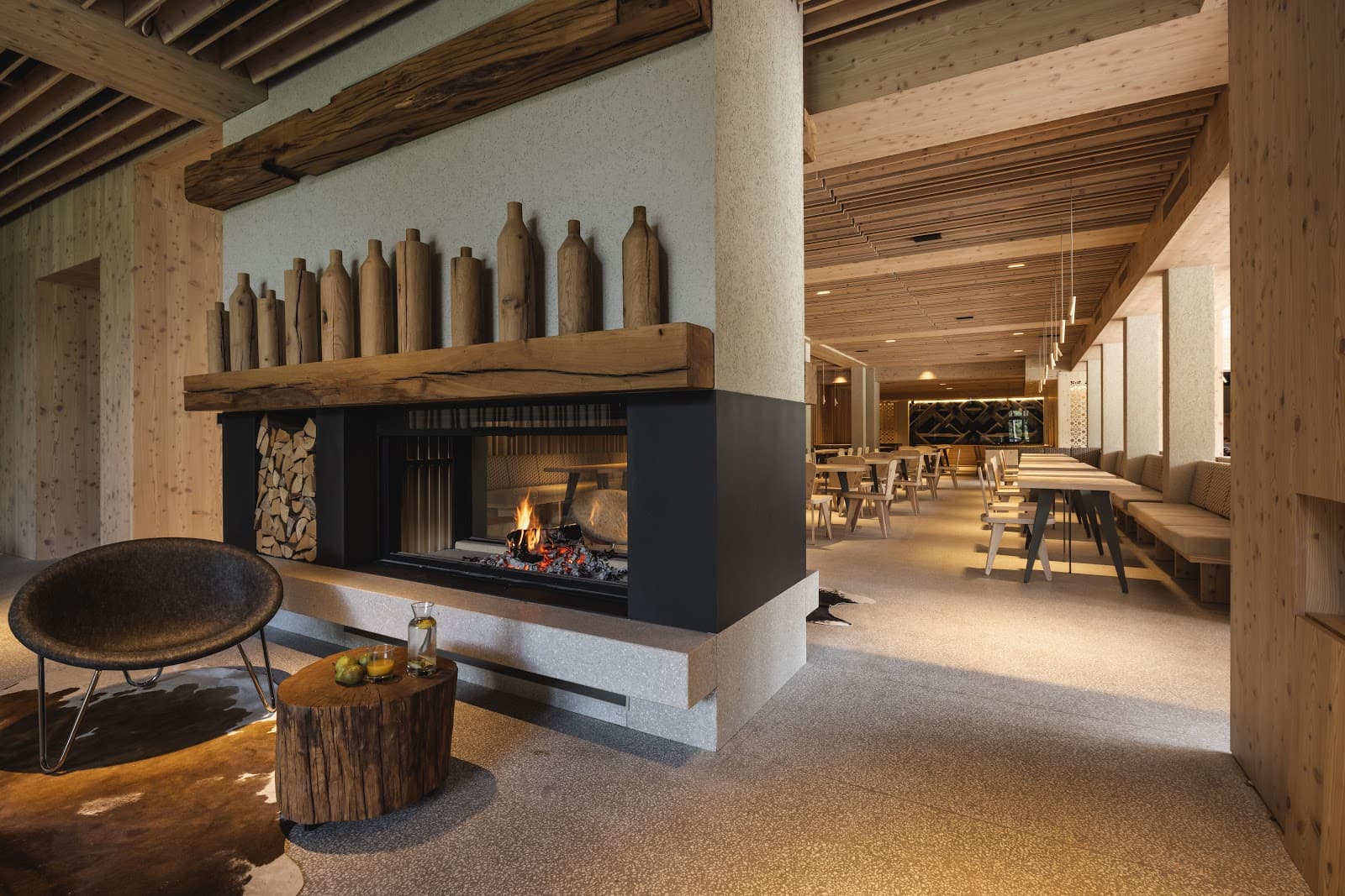 Lobby with large stone fireplace, wood decor, and adjacent dining area, likely in Bohinj.