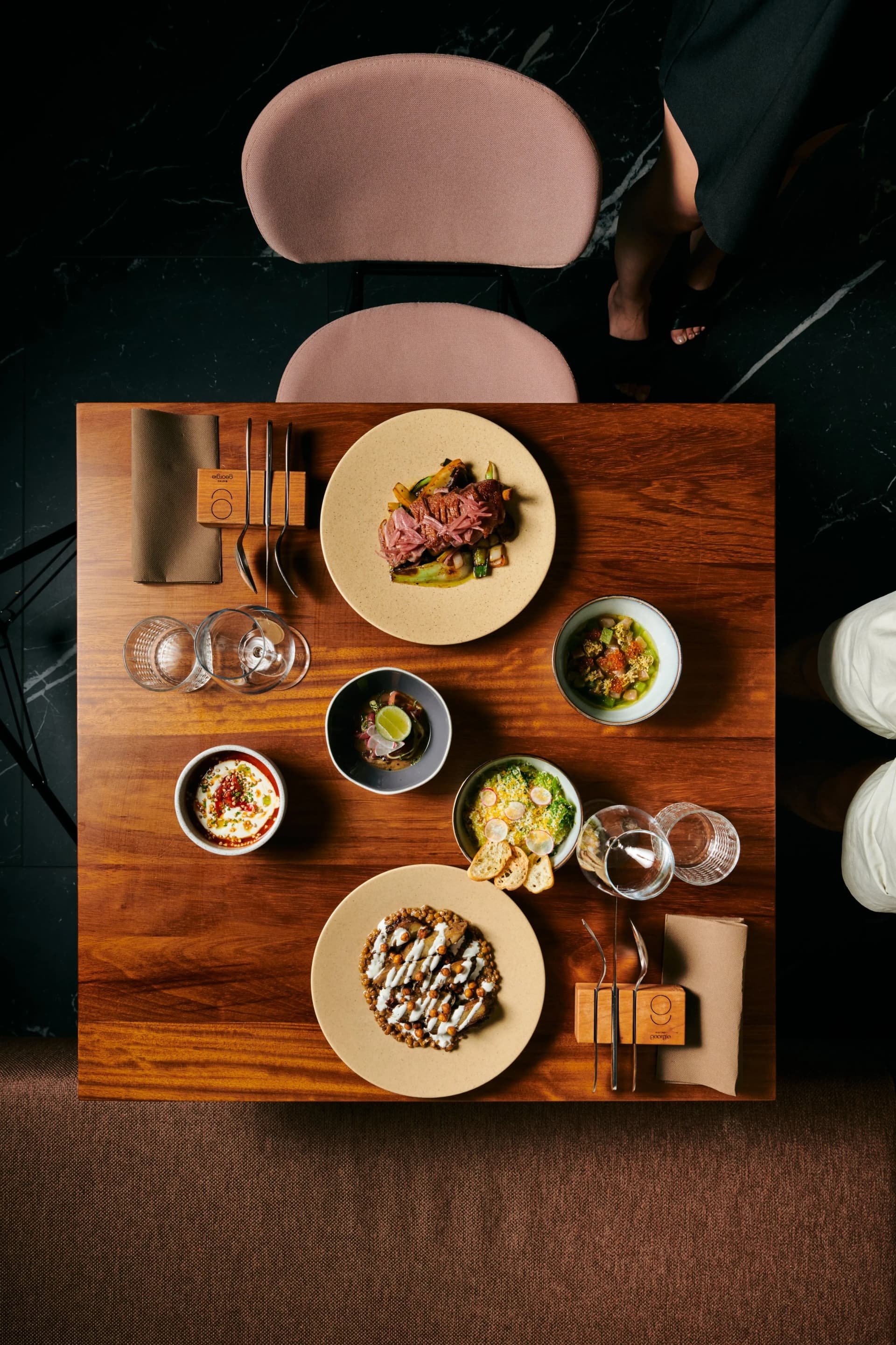 Overhead view of multiple gourmet dishes served on a wooden table at Georgie Bistro.