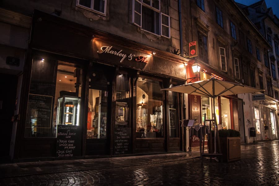 Marley & Me restaurant facade illuminated at night on a wet cobblestone street.