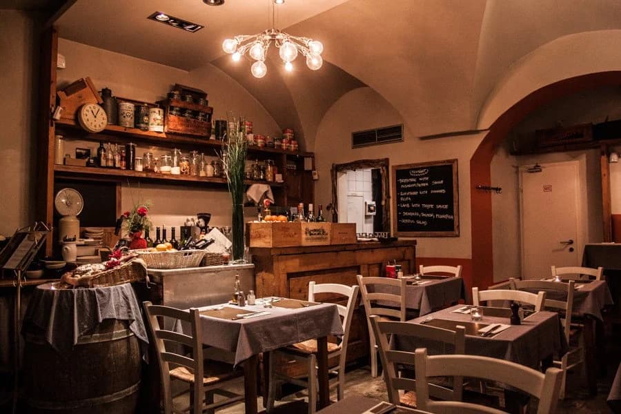 Cozy restaurant interior with vaulted ceiling, wooden counter, and set dining tables.