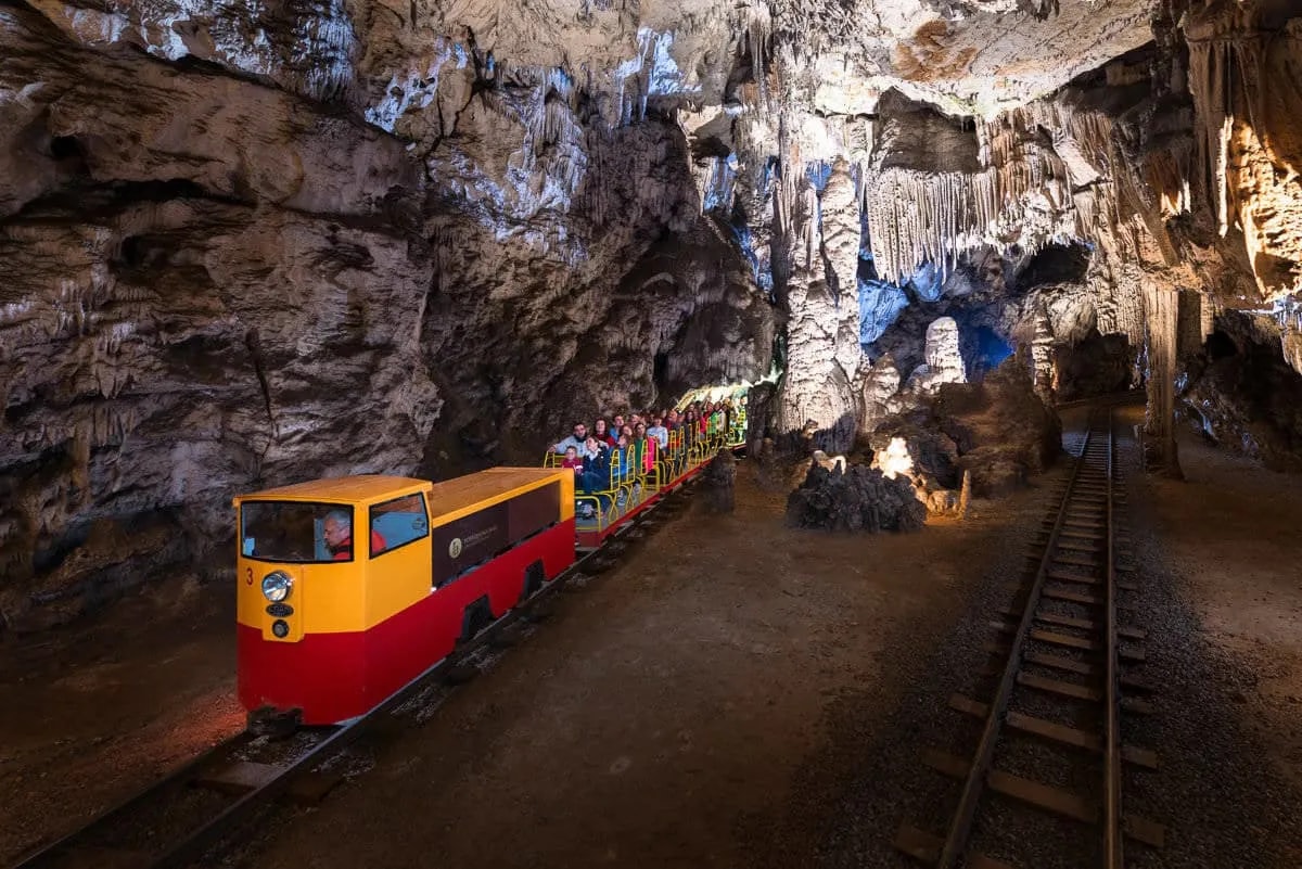 Postojna Cave train carrying visitors through cavern illuminated by artificial lights