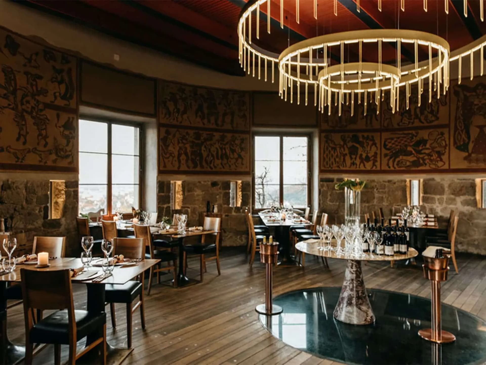 Dining room interior of Strelec Restaurant Ljubljana with stone walls and modern chandeliers.