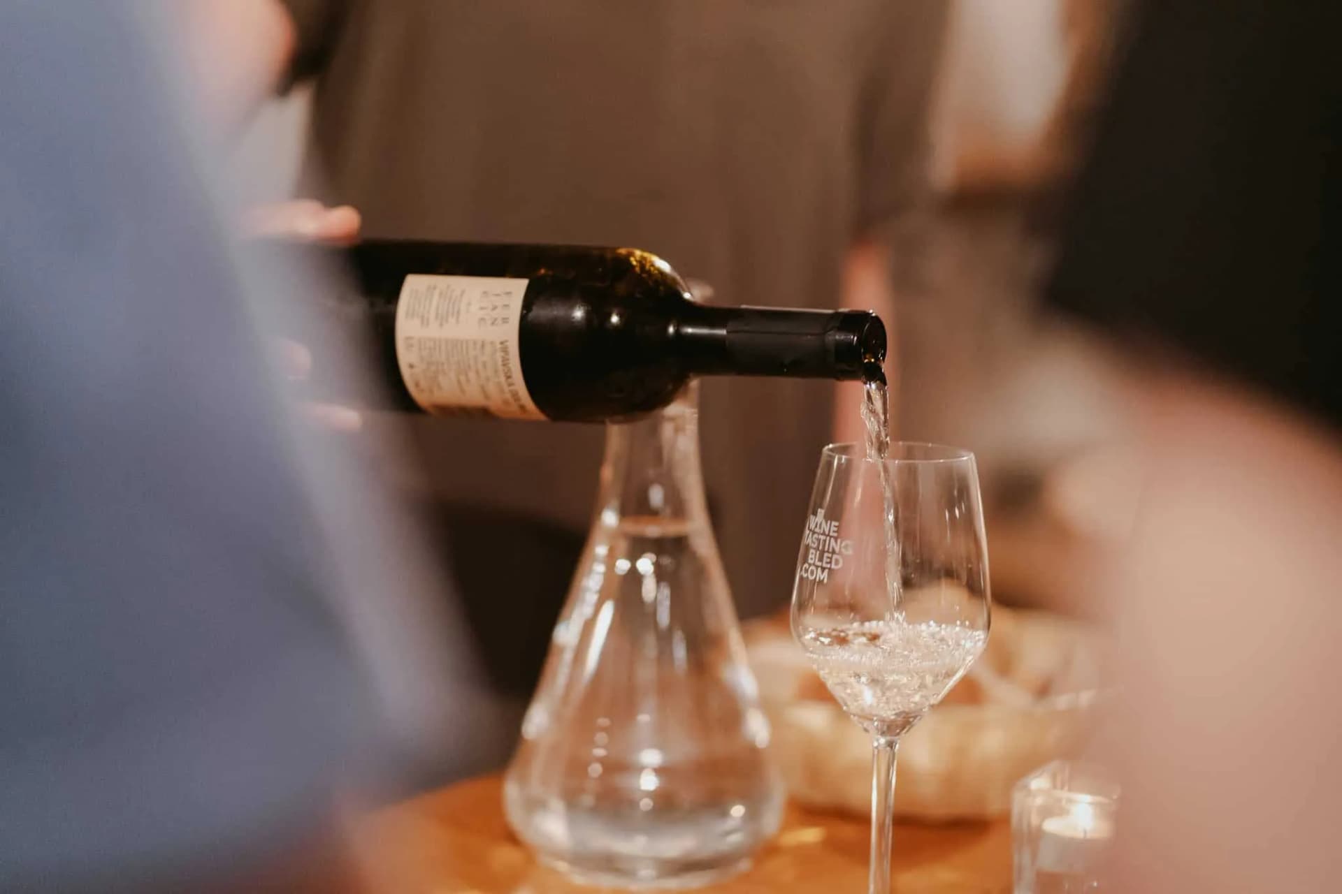 Wine being poured from a dark bottle into a glass during a tasting in Slovenia.
