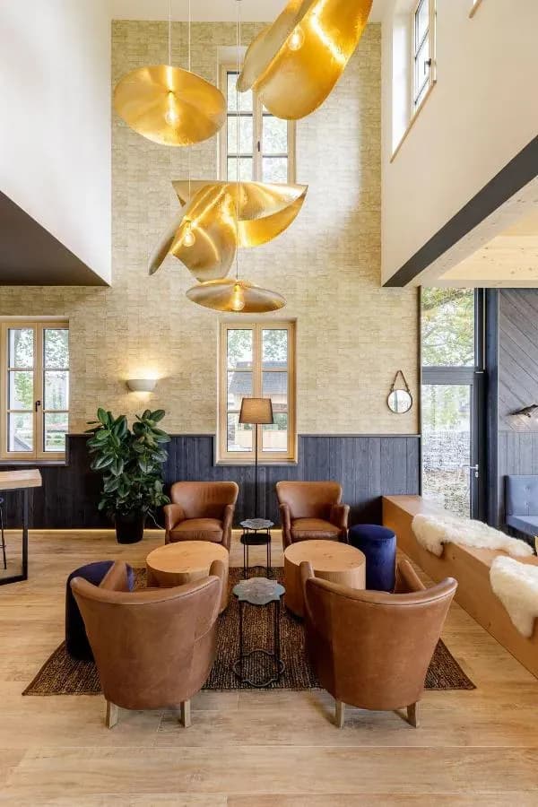 Lounge area with brown leather chairs, wood tables, and large gold sculptural pendant lights