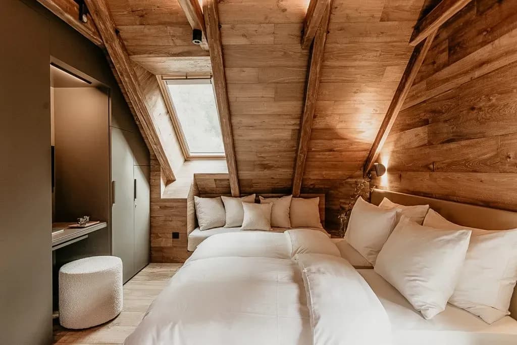 Attic bedroom with wood paneling, sloped ceiling, skylight, and white bedding.