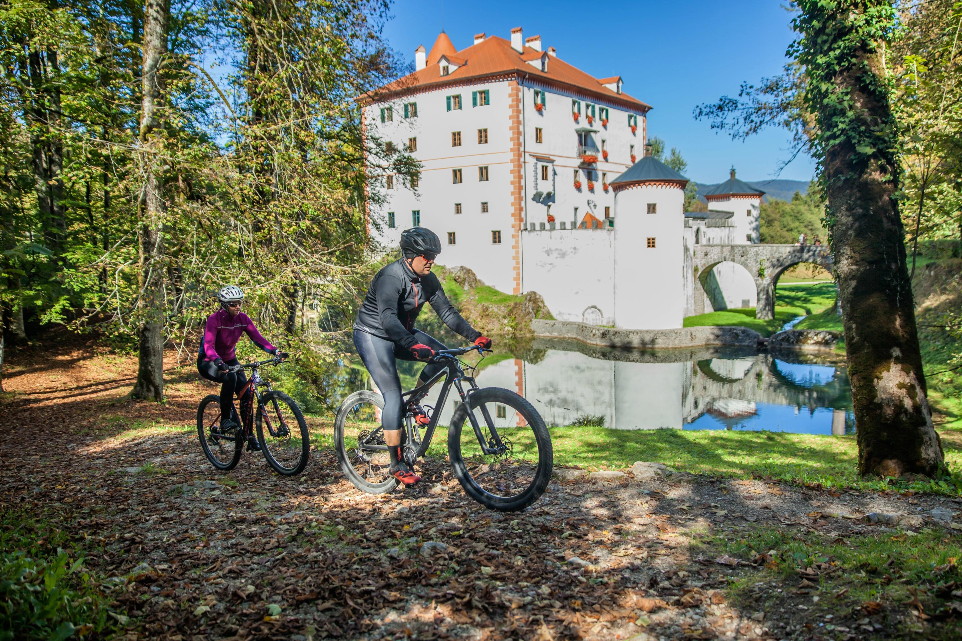 Tourists riding a bicycle near the beautiful Sneznik castle in Sneznik, Slovenia