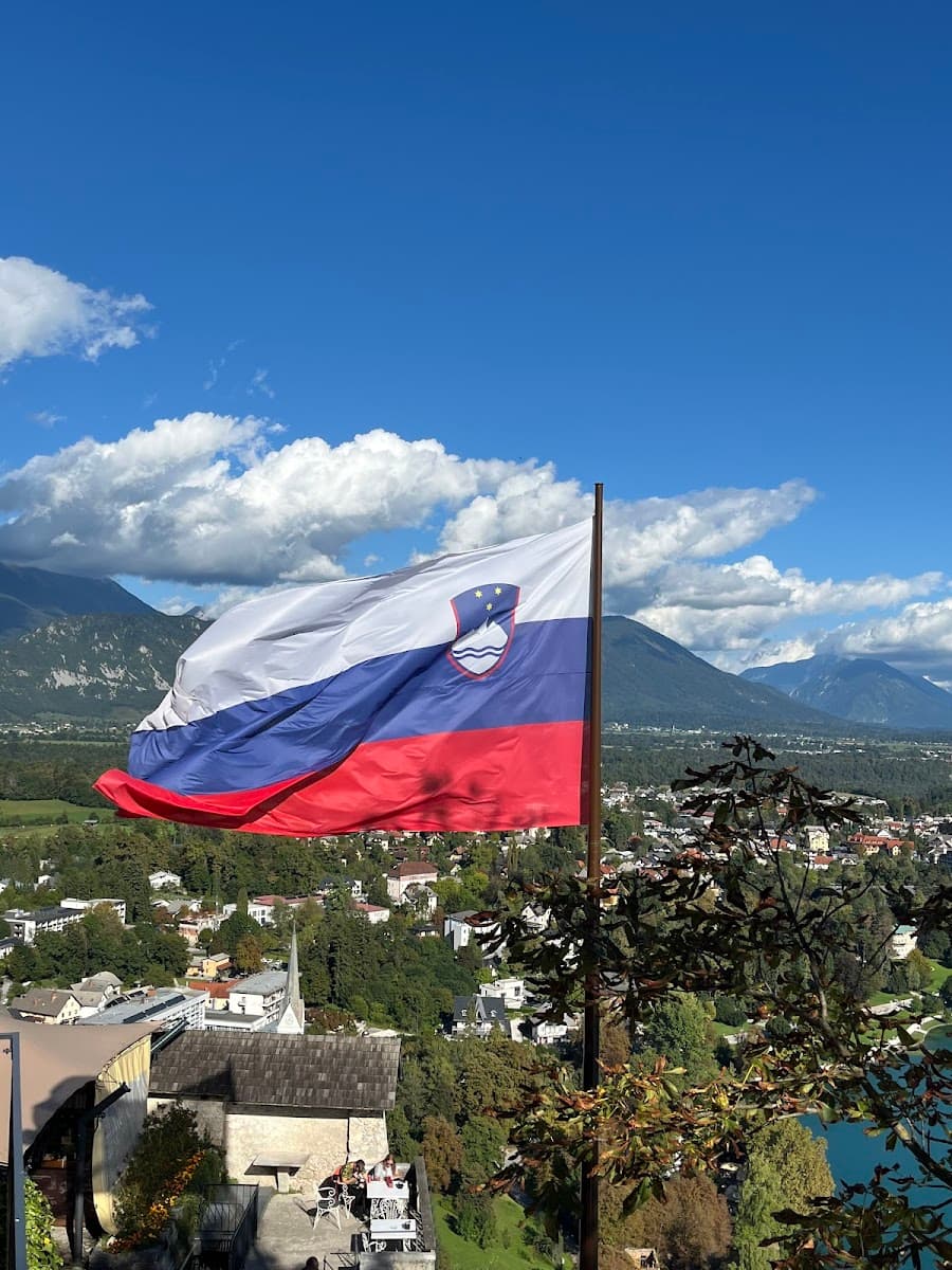 Slovenian flag flying over town and mountains, likely Lake Bled area