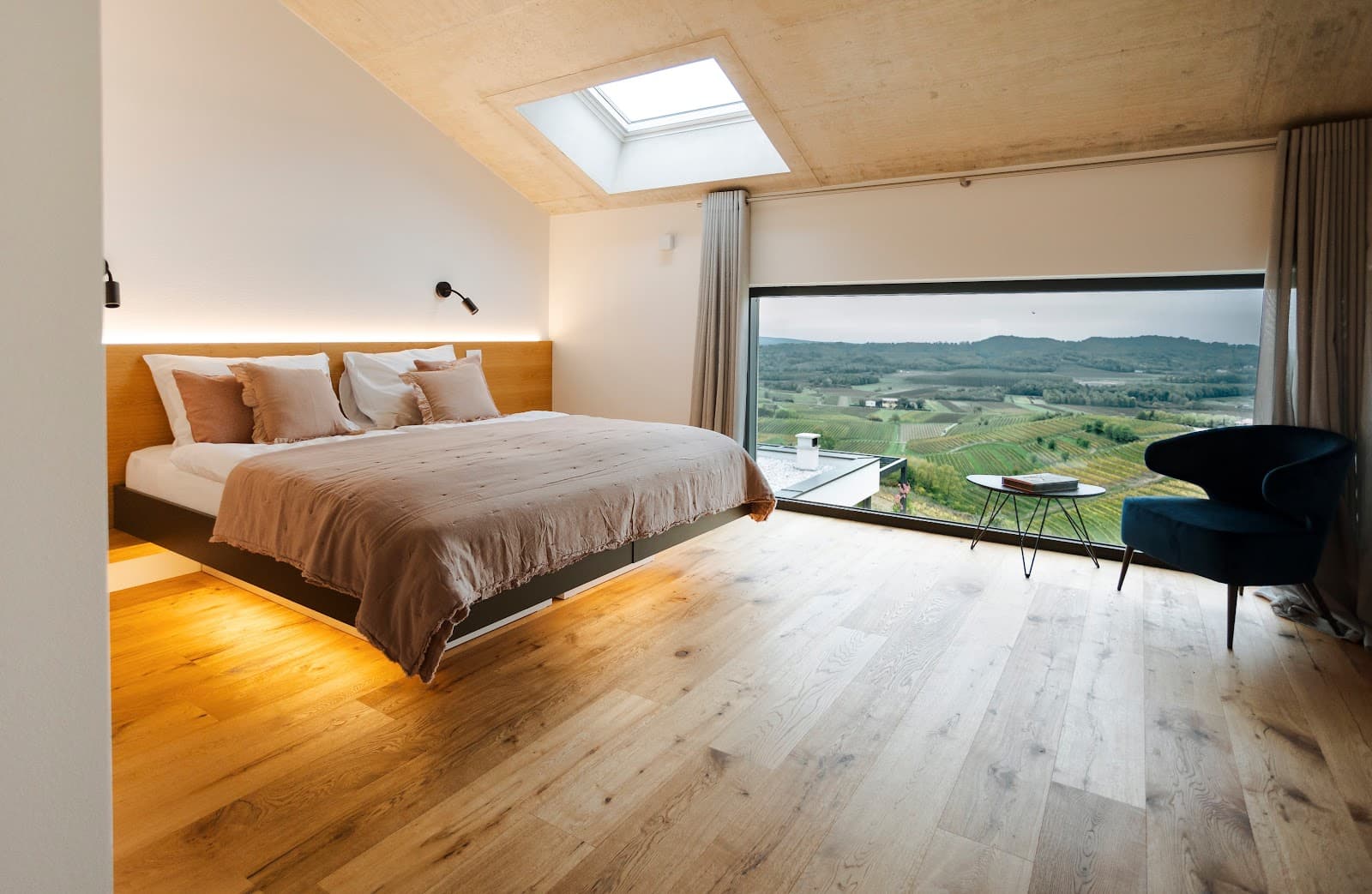 Modern bedroom with wood floors overlooking green rolling vineyards and hills