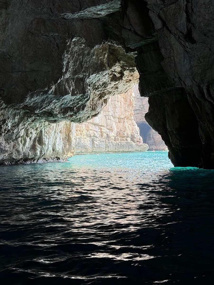 Sea cave opening to turquoise water and rocky cliffs